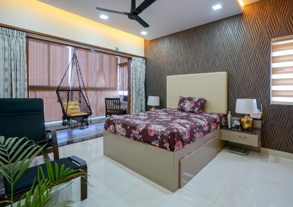 Modern bedroom with floral bedding, textured wall, and a balcony swing chair.